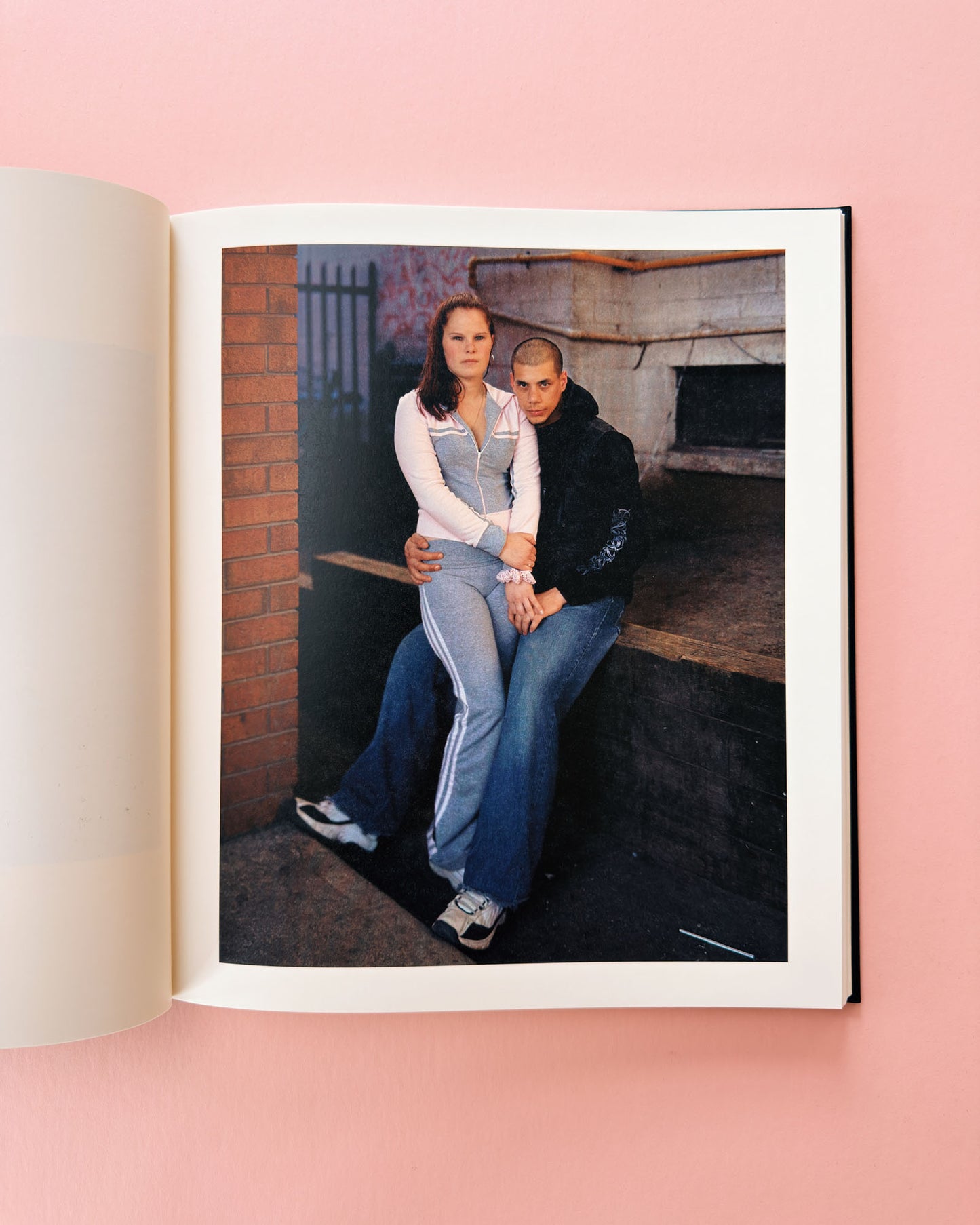 Open book showing a photograph of two people sitting together on a ledge. Classic photo book Niagara by Alec Soth. Made with large format film photography.