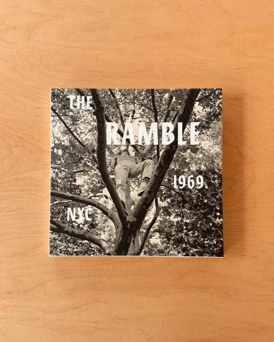 A square printed cover or book/poster titled "THE RAMBLE 1969 NYC" with a black-and-white photo of a person climbing a tree, placed on a light wood surface.